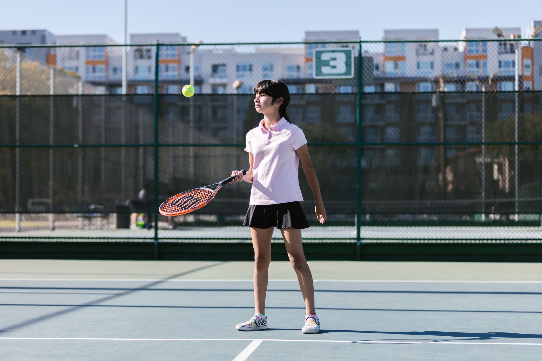 Girl in sportswear practicing tennis outdoors on a sunny day