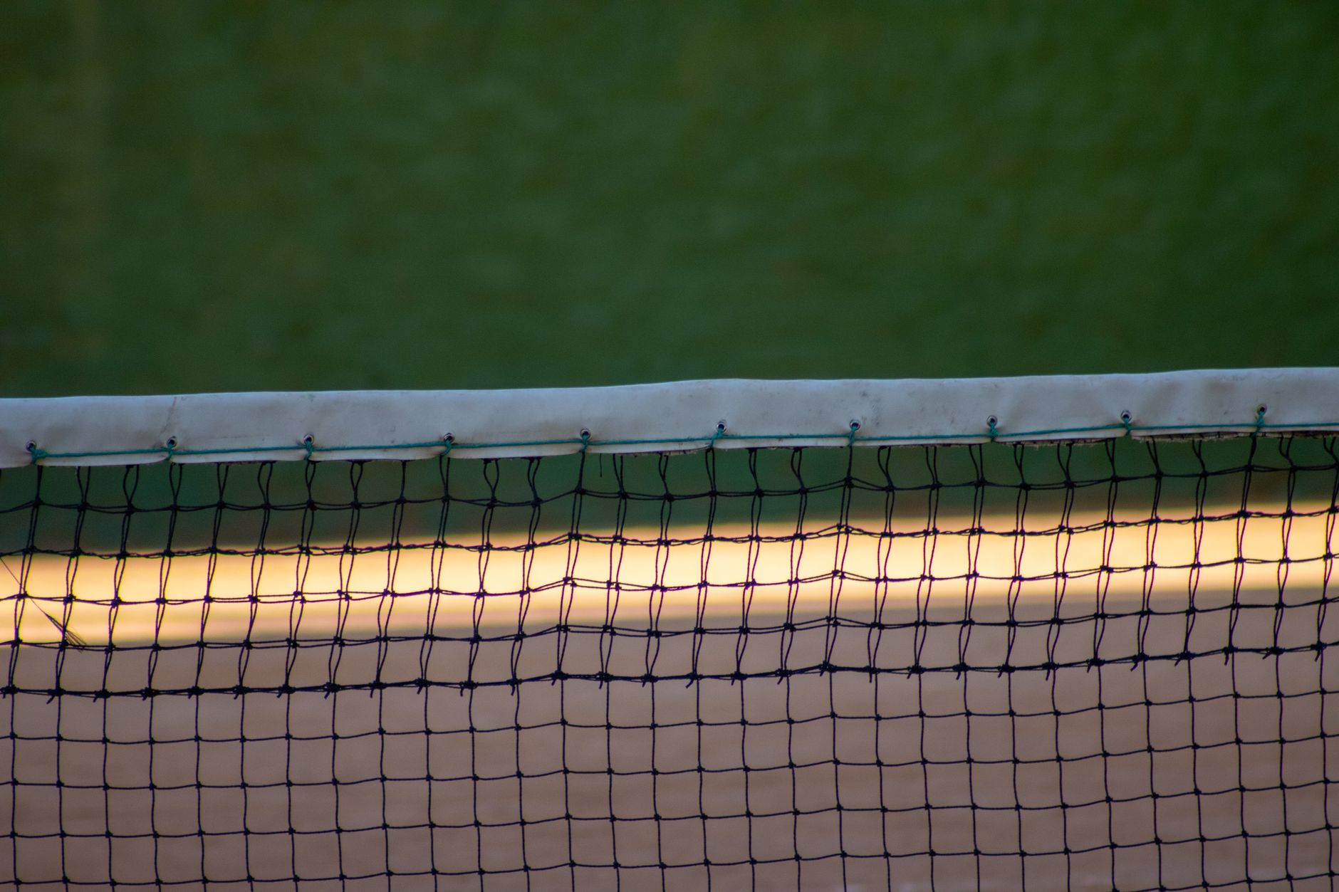 Close-up of a tennis net on a court in the evening light