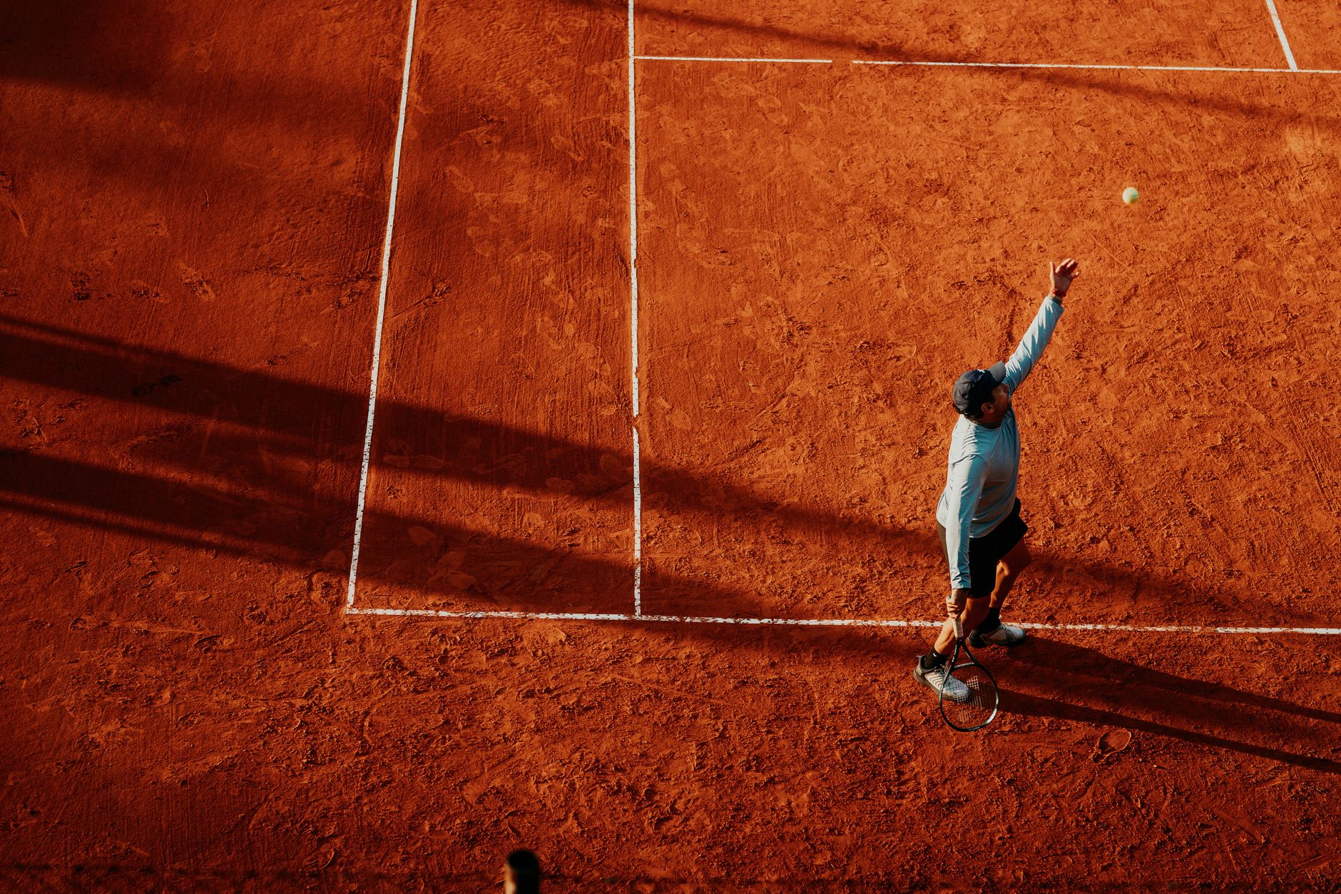 Aerial view of a tennis player serving on a clay court