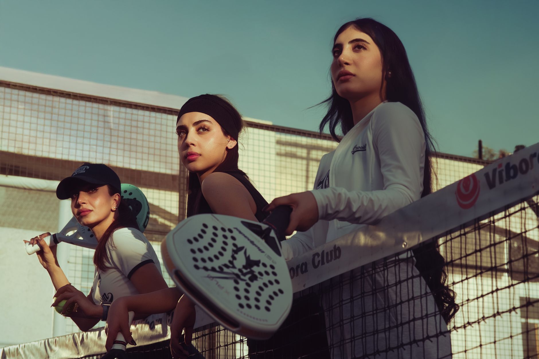 Three women playing padel tennis on an outdoor court