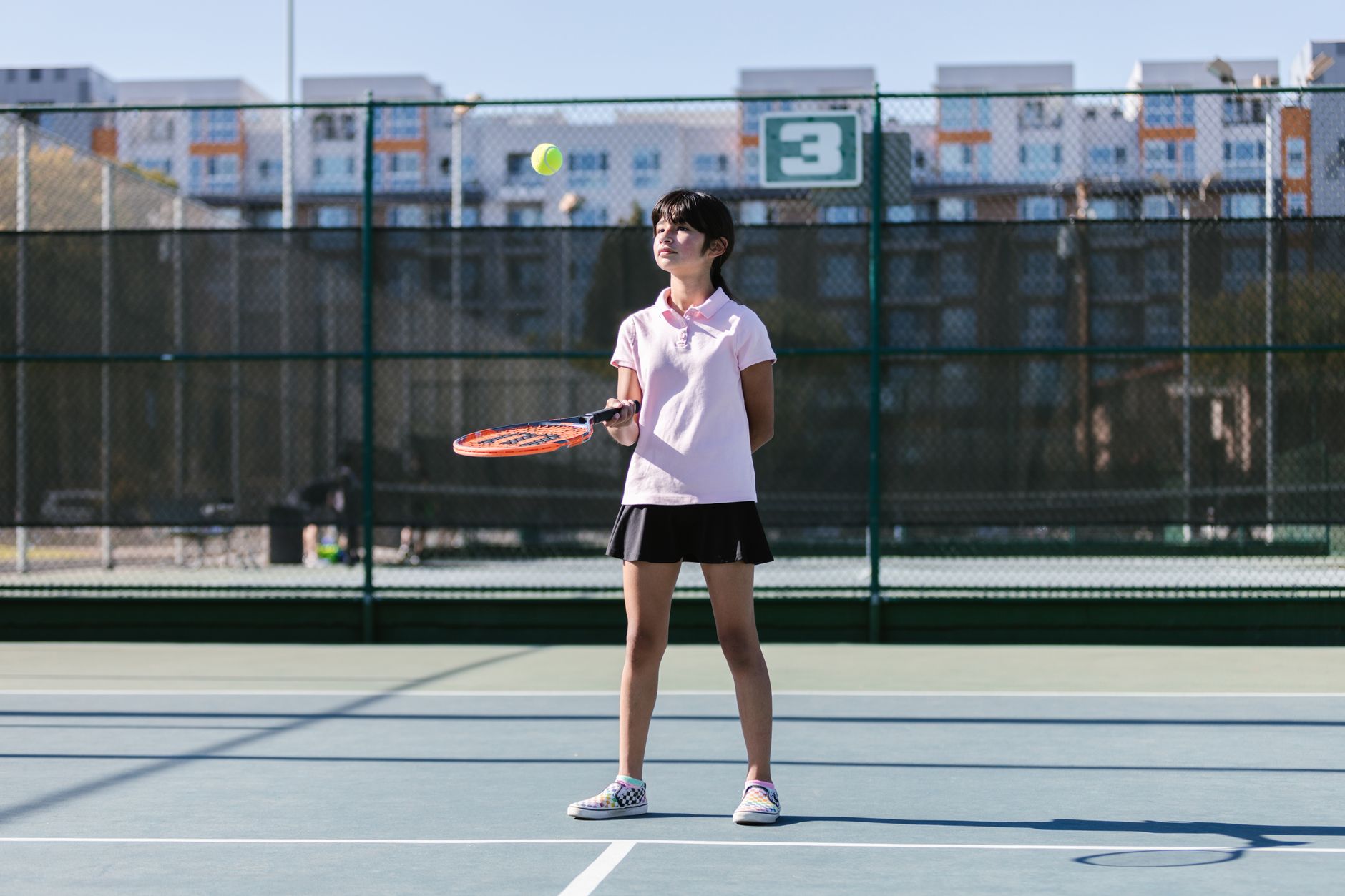 A player practicing her serve on a sunny outdoor tennis court