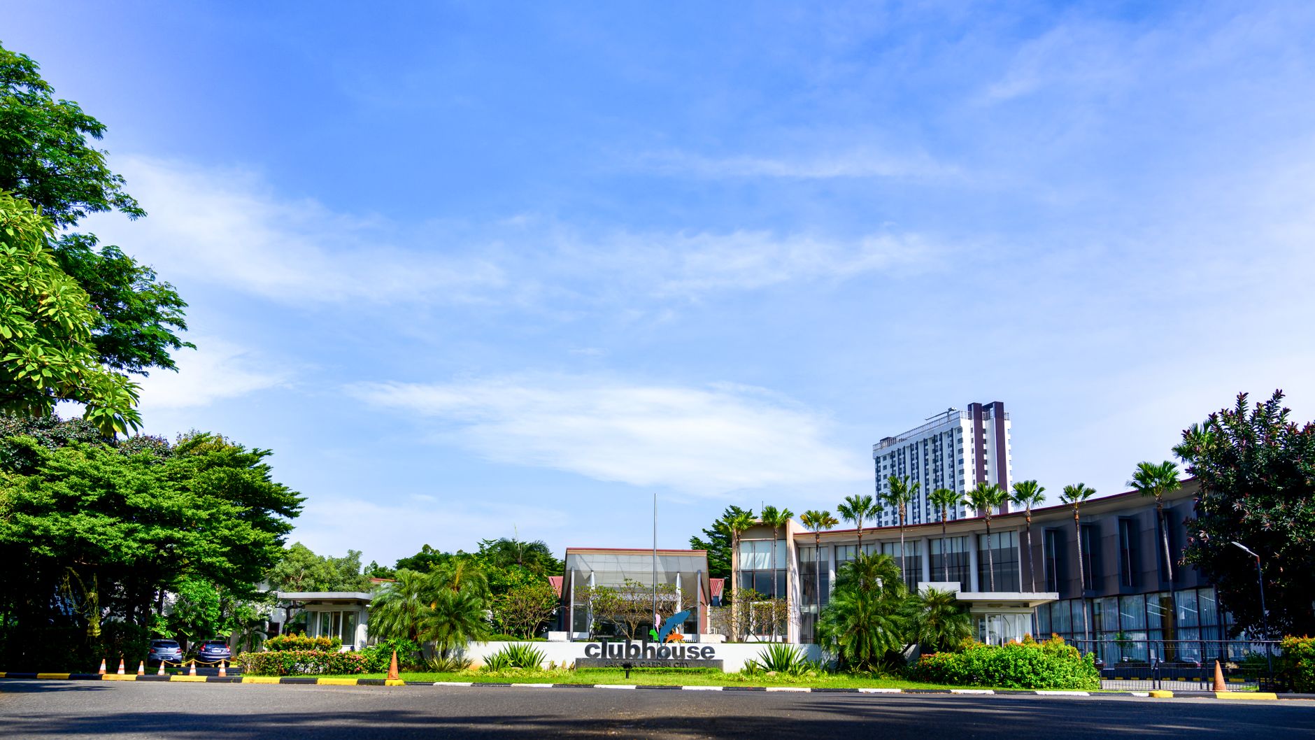 A contemporary clubhouse surrounded by lush greenery on a sunny day