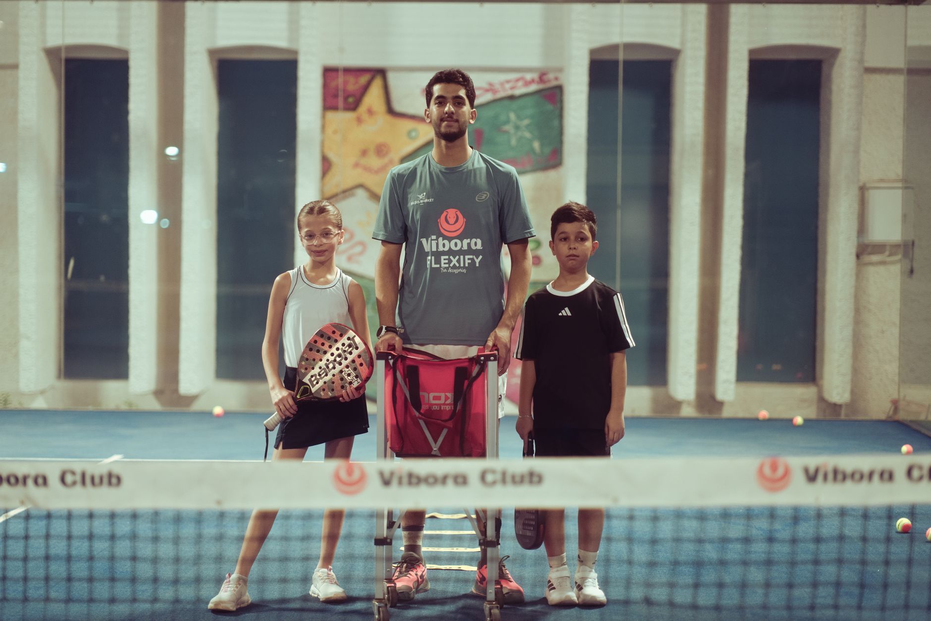 Tennis coach working with young players on an indoor court