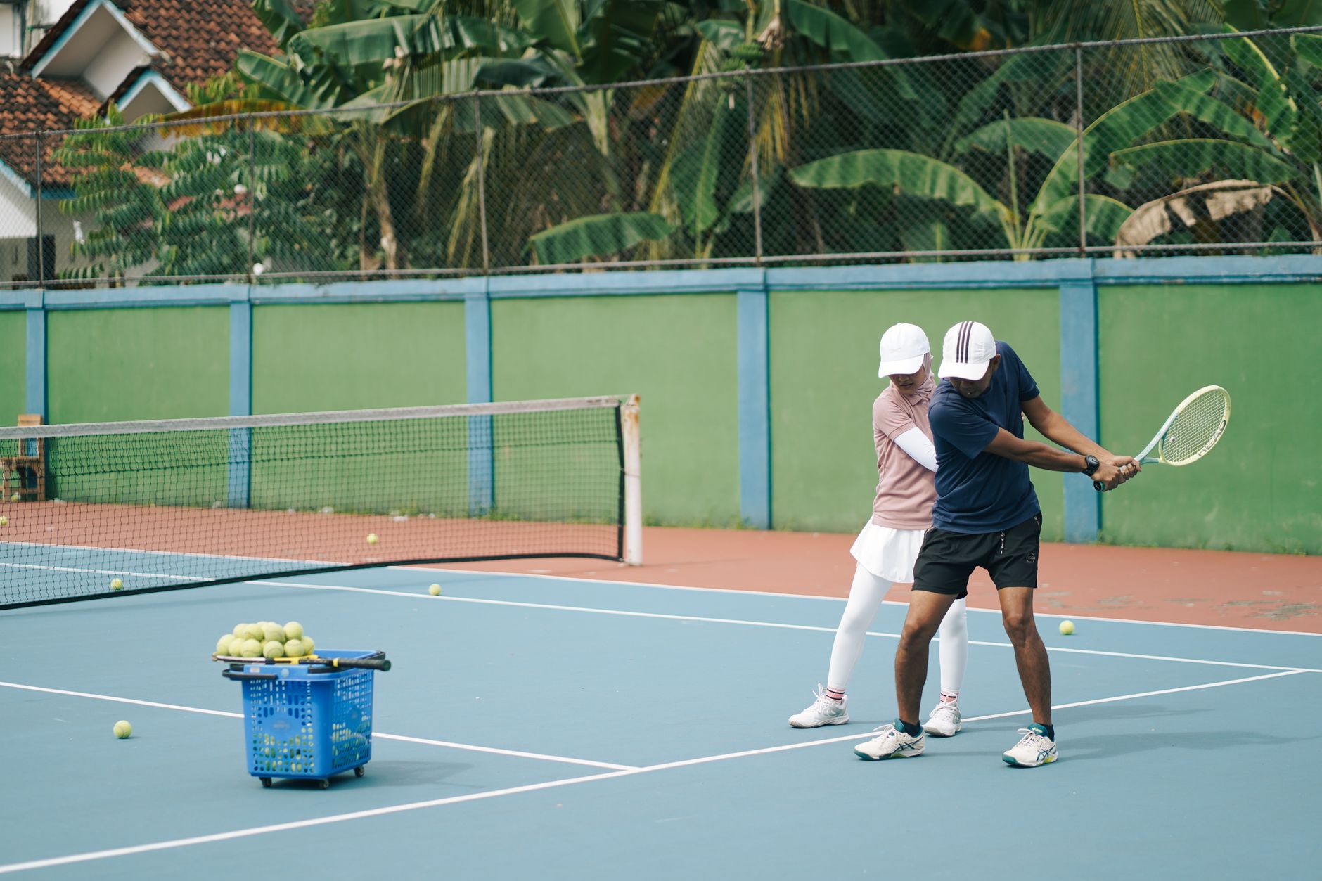 Tennis coach giving a lesson on a sunny outdoor court