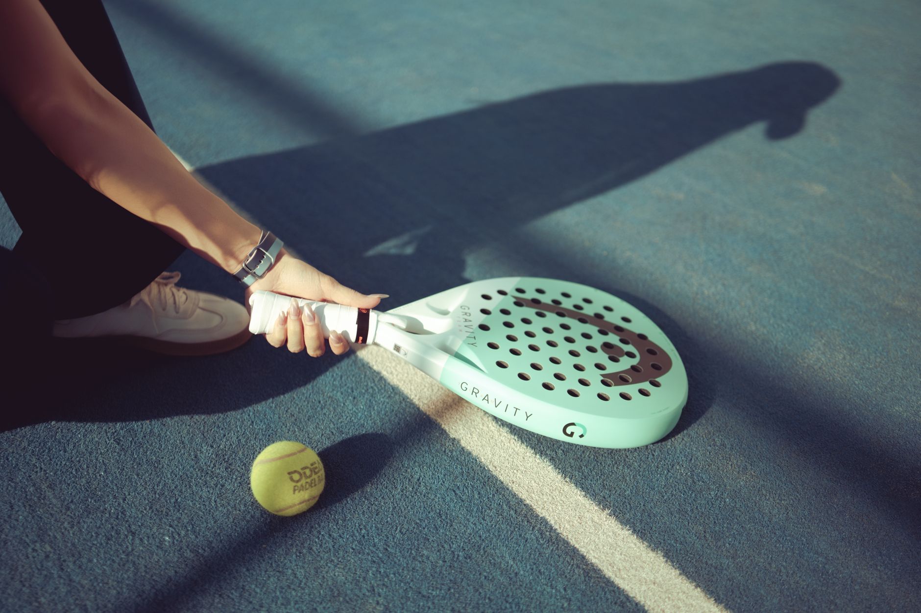 Padel player holding a racket on a sunlit outdoor court